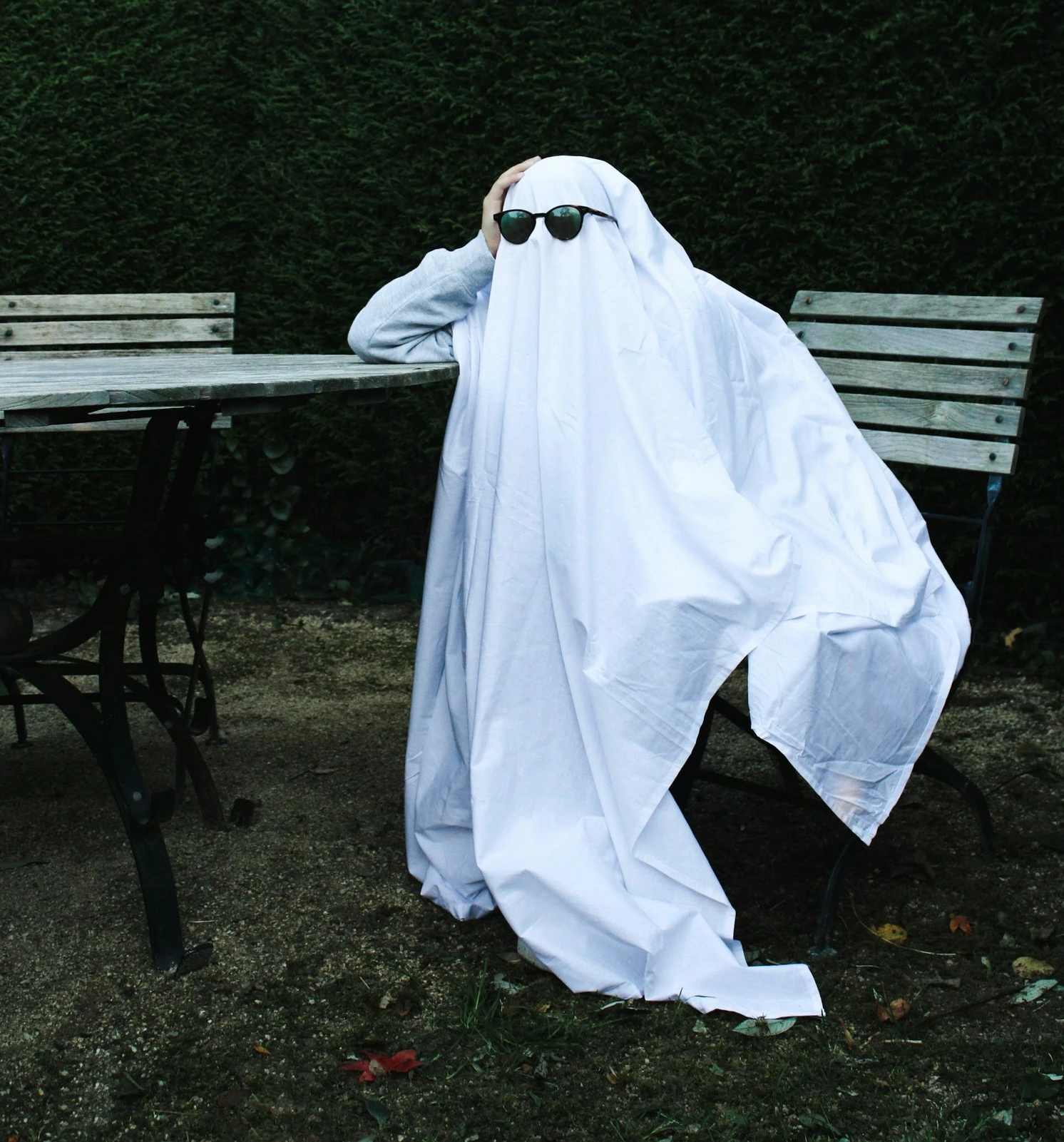 a person in a white robe and sunglasses sitting at a table